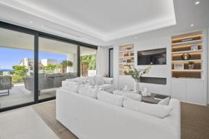 uma sala de estar com mobiliário branco e portas de vidro deslizantes em Villa Alejandra - Benahavis em Estepona