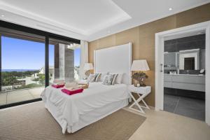 um quarto com uma grande cama branca e uma grande janela em Villa Alejandra - Benahavis em Estepona