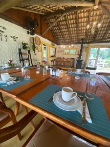 una mesa de madera con platos y tazas de café. en Hotel Fazenda Bom Retiro en Quatis