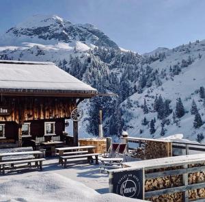 a building with benches and a snow covered mountain at Mount74 in Zürs am Arlberg