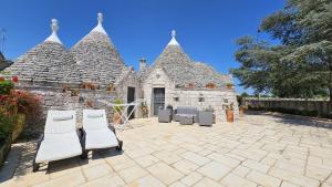 a patio with chairs and a stone building at Trulli in Valle D'Itria in Cisternino