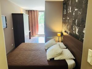 a bedroom with a bed with two pillows on it at L'HOTEL DE LA BOURSE à BAGNOLS-SUR-CEZE in Bagnols-sur-Cèze