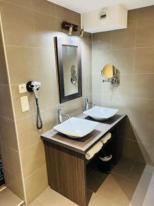 a bathroom with two sinks and a phone at L'HOTEL DE LA BOURSE à BAGNOLS-SUR-CEZE in Bagnols-sur-Cèze