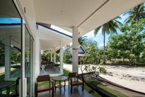 een open veranda van een huis met een tafel en stoelen bij All At Sea Beach Resort in Baan Tai