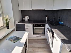 una cocina con armarios blancos y una mesa con fregadero en Dzintaru apartamenti, en Mērsrags