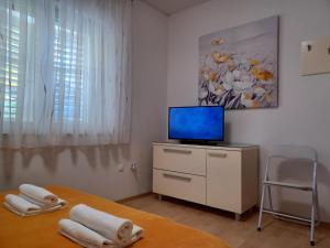 een slaapkamer met een tv en een bed met handdoeken bij MG Ravlic Apartments in Makarska