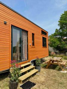 una casita naranja pequeña con una mesa de picnic y un banco en Tiny House et chevaux en Le Breuil
