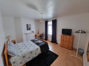 戈斯波特Mayfield , 2 bed slp 6 Roomy dog friendly Gosport town house的一间卧室配有一张床、一台电视和一个梳妆台