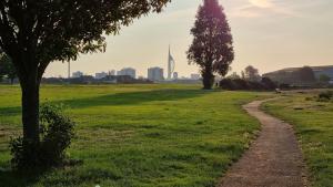 a path in a park with a city in the background at Roomy dog friendly Gosport town house sleeps 6 in Gosport