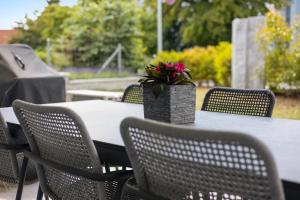 einen Tisch mit Stühlen und eine Vase mit einer Blume darauf in der Unterkunft The R Apartment Zugerberg - EV Wallbox - Terrasse in Geroldswil