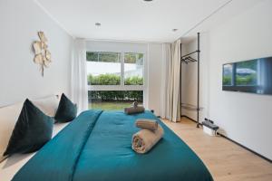 Cama grande azul en habitación con ventana grande en The R Apartment Zugerberg - EV Wallbox - Terrasse, en Geroldswil