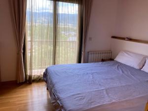 um quarto com uma cama e uma grande janela em Cal Mercadé em Puigcerdà