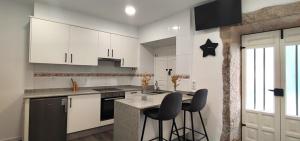 a kitchen with white cabinets and a counter with bar stools at Apartamento en playa de Laxe in Laxe