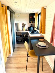 Joy Tiny House Perche في Madeleine: مطبخ صغير مع طاولة سوداء وكراسي صفراء