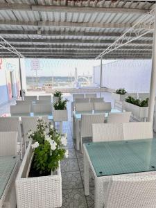 eine Terrasse mit weißen Stühlen, Tischen und Blumen in der Unterkunft Del Mar Koblevo in Koblewe