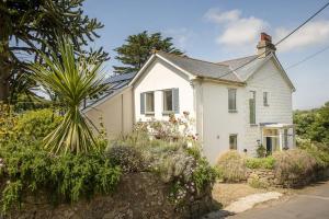 a white house with flowers in front of it at Treen House, Porthcurno in Porthcurno