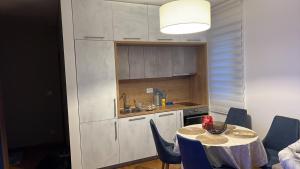 a kitchen with a table and blue chairs in a room at Apartman Jakov in Bečići +8 photos