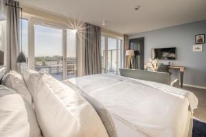 a bedroom with a white bed and a large window at Küstenperle Strandhotel & Spa in Büsum