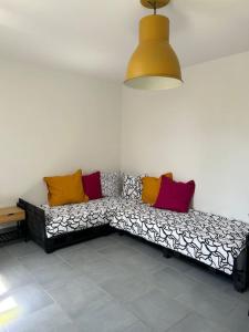 Un sofá blanco y negro con almohadas coloridas. en T2 maison entre calme & ville, en La Riche