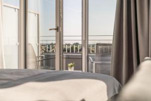 a bedroom with a bed and a large window at Küstenperle Strandhotel & Spa in Büsum