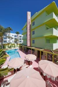 um hotel com guarda-sóis e uma piscina em Tropicana Ibiza Suites - Adults Only em Playa d'en Bossa