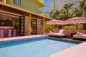 een zwembad met stoelen en parasols naast een gebouw bij Tropicana Ibiza Suites - Adults Only in Playa d'en Bossa