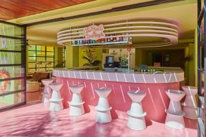 um restaurante com um balcão cor-de-rosa com cadeiras brancas em Tropicana Ibiza Suites - Adults Only em Playa d'en Bossa