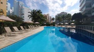 a large swimming pool with chairs and umbrellas at Alugar na Riviera Hotel Ilha da Madeira Resort in Riviera de São Lourenço