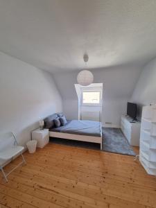 a white bedroom with a bed and a window at Süße Marie 2 in Karlsruhe +3 photos