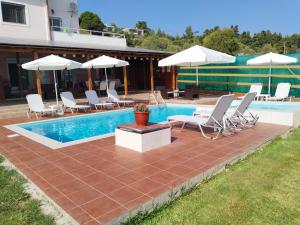 a swimming pool with chairs and umbrellas next to a house at Maria Lemoni swimming pool apartment in Nea Skioni