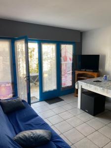 a living room with a blue couch and sliding glass doors at Chambre indépendante dans une villa in Saint-Trojan-les-Bains