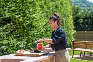 Eine Frau schneidet eine Wassermelone auf dem Tisch in der Unterkunft Residence Toli in Ledro