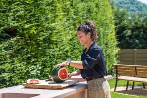 a woman is cutting a watermelon on a table at Residence Toli in Ledro
