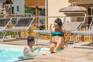 a man and a woman in a swimming pool at CROSINA HOLIDAY - Residence Toli in Ledro