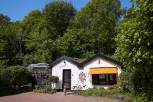 ein kleines weißes Haus mit orangefarbenem und schwarzem Dach in der Unterkunft Zandrijk in Egmond aan den Hoef