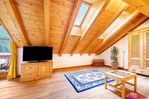 a living room with wooden ceilings and a flat screen tv at Mitterbruggehof Apt Berganemone in Anterselva di Mezzo