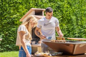 a man and a woman preparing food on a grill at Residence Toli in Ledro