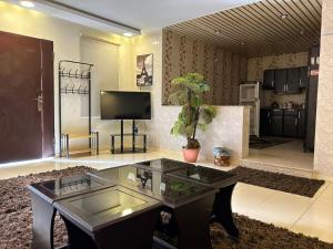 ein Wohnzimmer mit einem Glastisch und einem TV in der Unterkunft ليلتنا in Ha'il