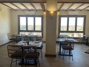 uma sala de jantar com mesas, cadeiras e janelas em Alkalea Hospedería em Alcalá del Júcar