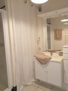 une salle de bain blanche avec un lavabo et un miroir dans l'établissement Le Guépratte, à Granville