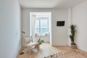 a white living room with a chair and a window at Hotel del Mar in Sanxenxo
