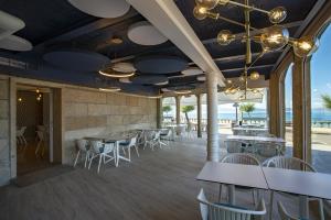 a restaurant with tables and chairs and the beach at Hotel del Mar in Sanxenxo
