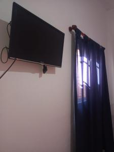 TV de pantalla plana colgada en una pared junto a una ventana en Normi en La Rioja