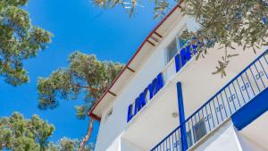 a white building with blue windows and trees at Likya Inn in Karadere