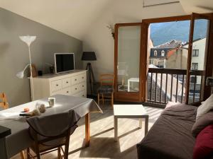 a living room with a table and a balcony at Le Perce Neige - plein centre in Luchon