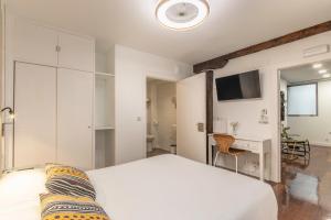 1 dormitorio con 1 cama blanca grande y escritorio en Victorooms, en Bilbao