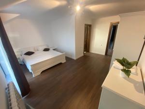Schlafzimmer mit einem weißen Bett und Holzboden in der Unterkunft Casa Ambientt in Albestii de Arges