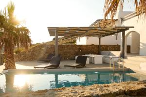 una piscina con due sedie a sdraio e un pergolato di Villa Alitis by Mykonos Rocks a Mykonos Città