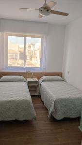 two beds in a room with a window at CABALLITO DE MAR in Los Alcázares