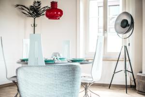 stół jadalny z białymi krzesłami i czerwoną lampką w obiekcie Tilia Apartments w mieście Uster